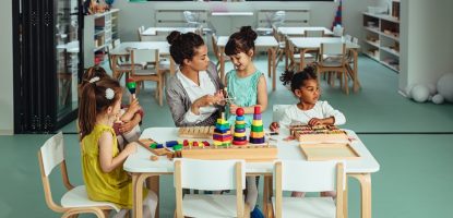 Teacher is playing with cheerful children at kindergarten